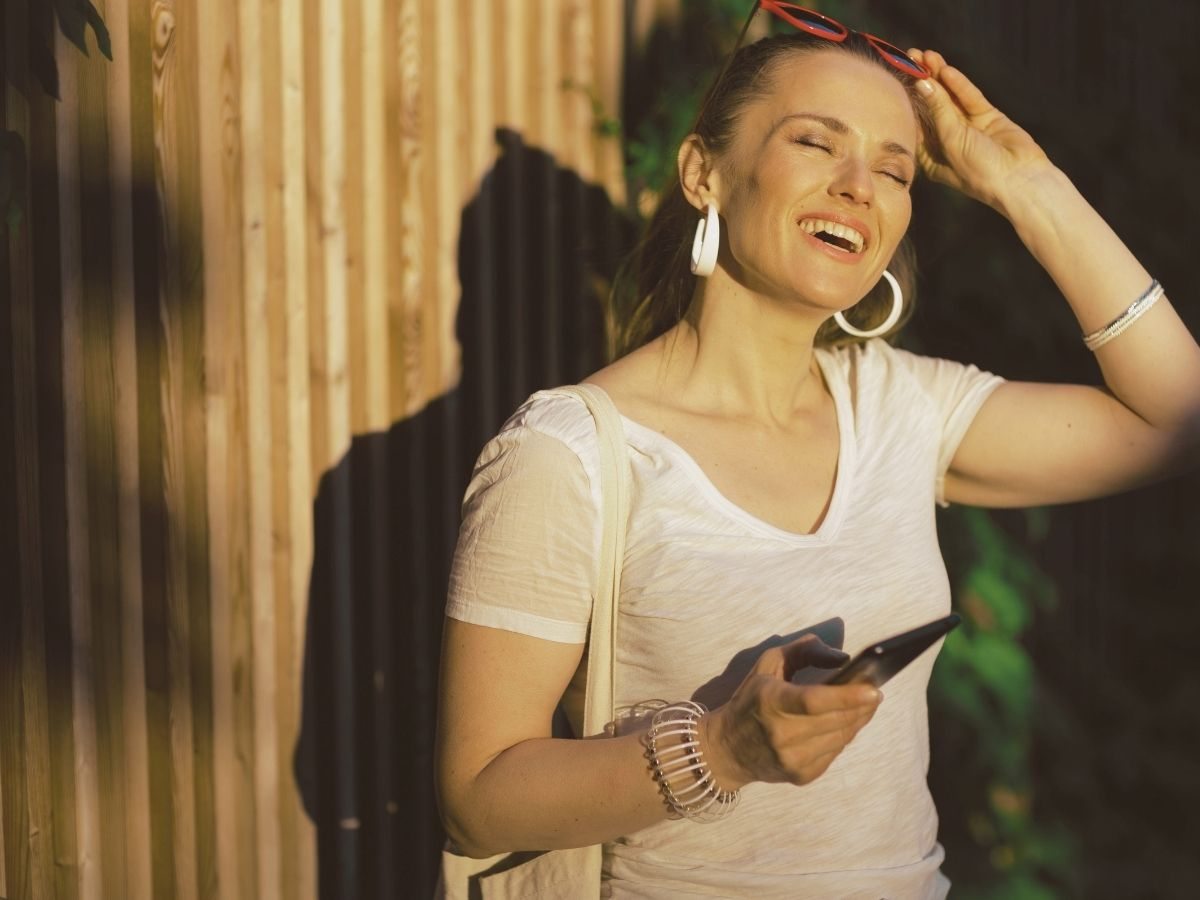 A mesma mulher recostada na cadeira, ombros relaxados, sorrindo para a tela do notebook